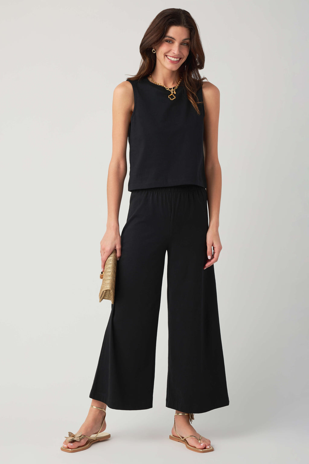 Black sleeveless jersey muscle tank with crew neck and relaxed fit, with wide-leg pants.