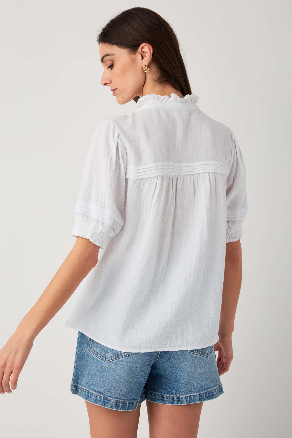 White gauze short-sleeve button blouse, back view with yoke band and ruffle trim.