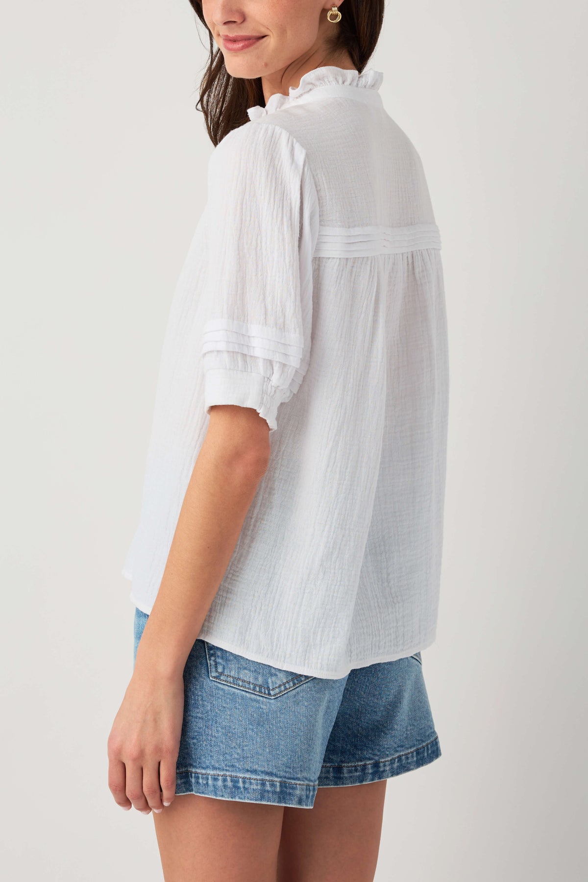 White gauze short-sleeve button blouse with ruffle collar and tiered sleeve details.