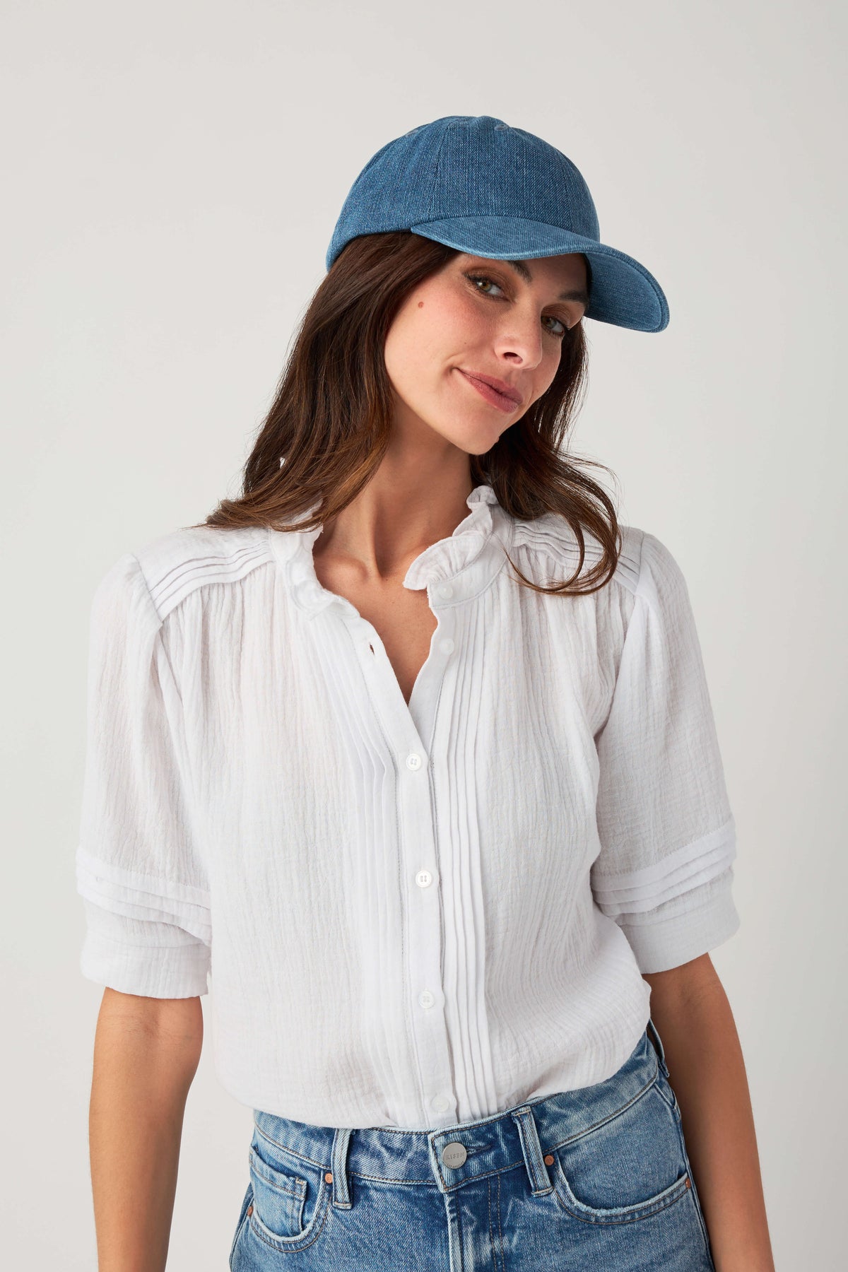 Denim blue baseball cap with curved brim, model looking to the side