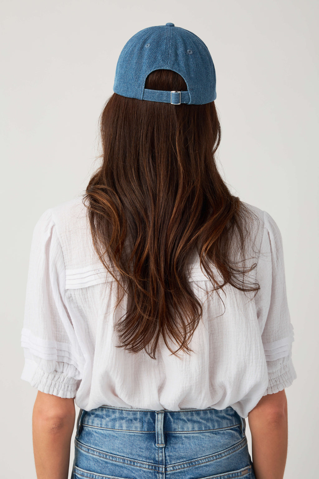 Denim blue baseball cap shown from behind with curved brim and strapback