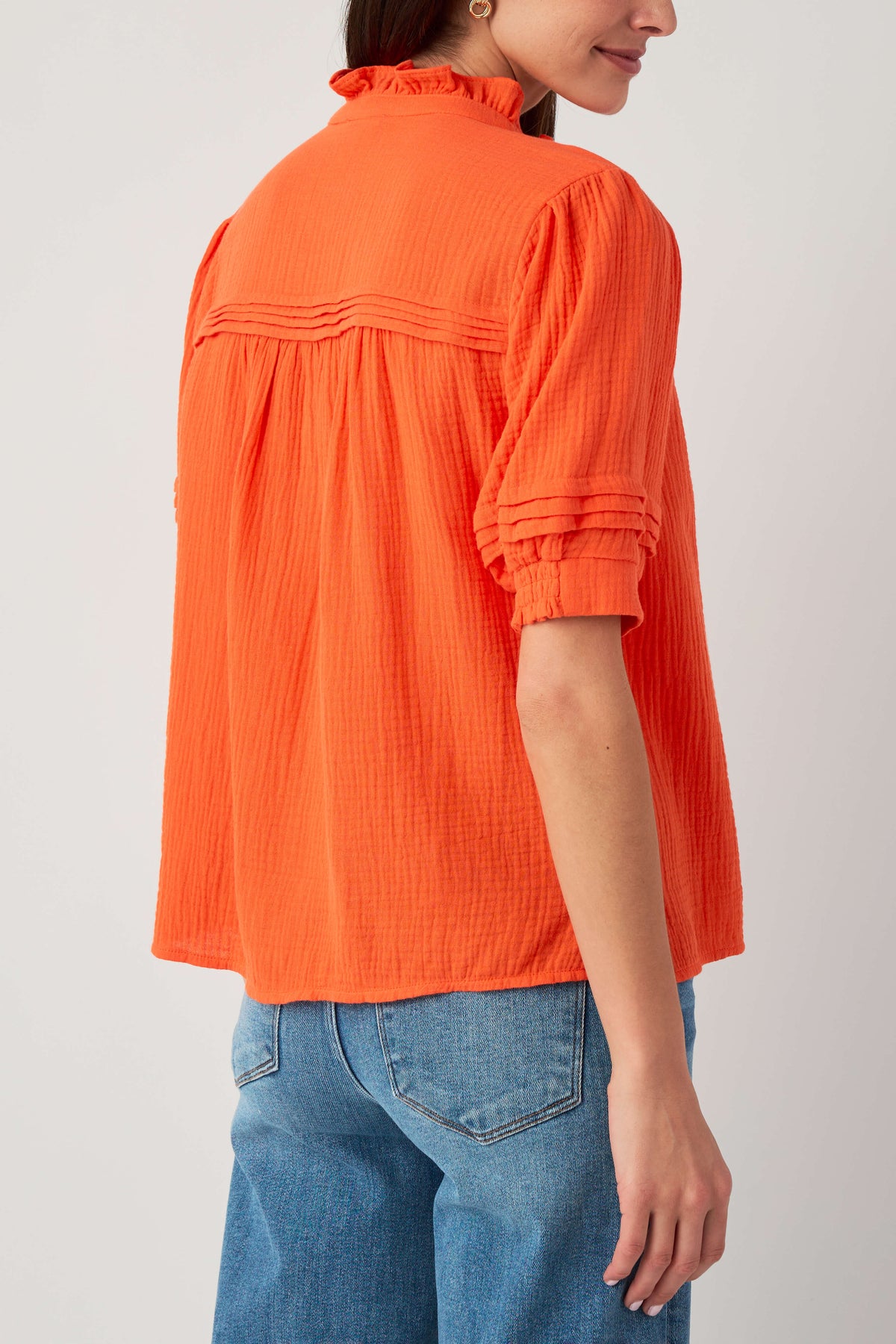 Coral gauze short sleeve top, back/side view with yoke ruffles and elastic cuffs
