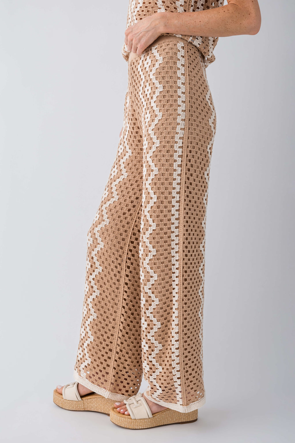 Close-up of natural wide-leg crochet pants with repeating zigzag trim and texture