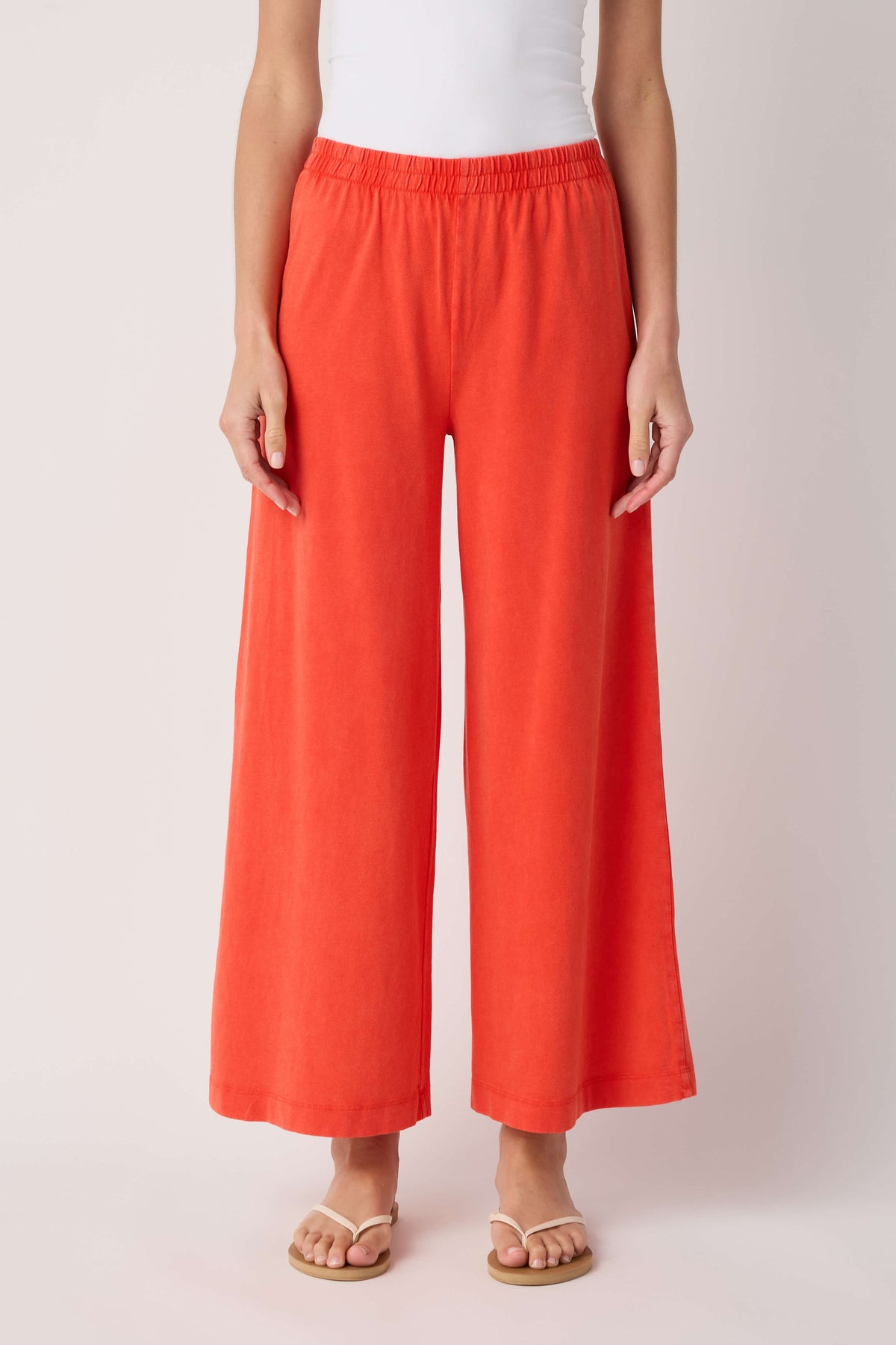 Jersey crop flare pants in coral orange, elastic waist, wide flared legs.