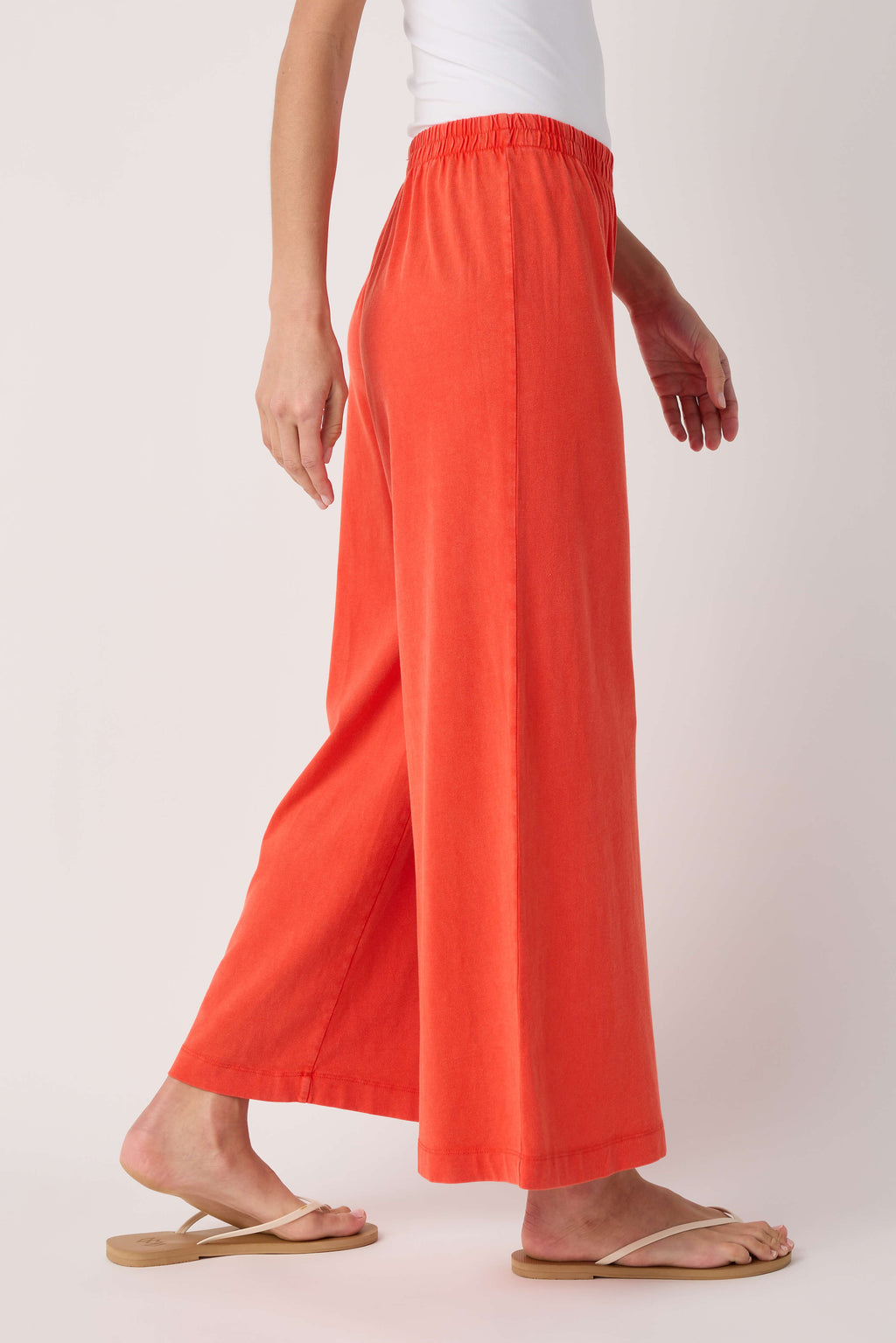 Jersey crop flare pants in coral orange, elastic waist, wide flared side view.