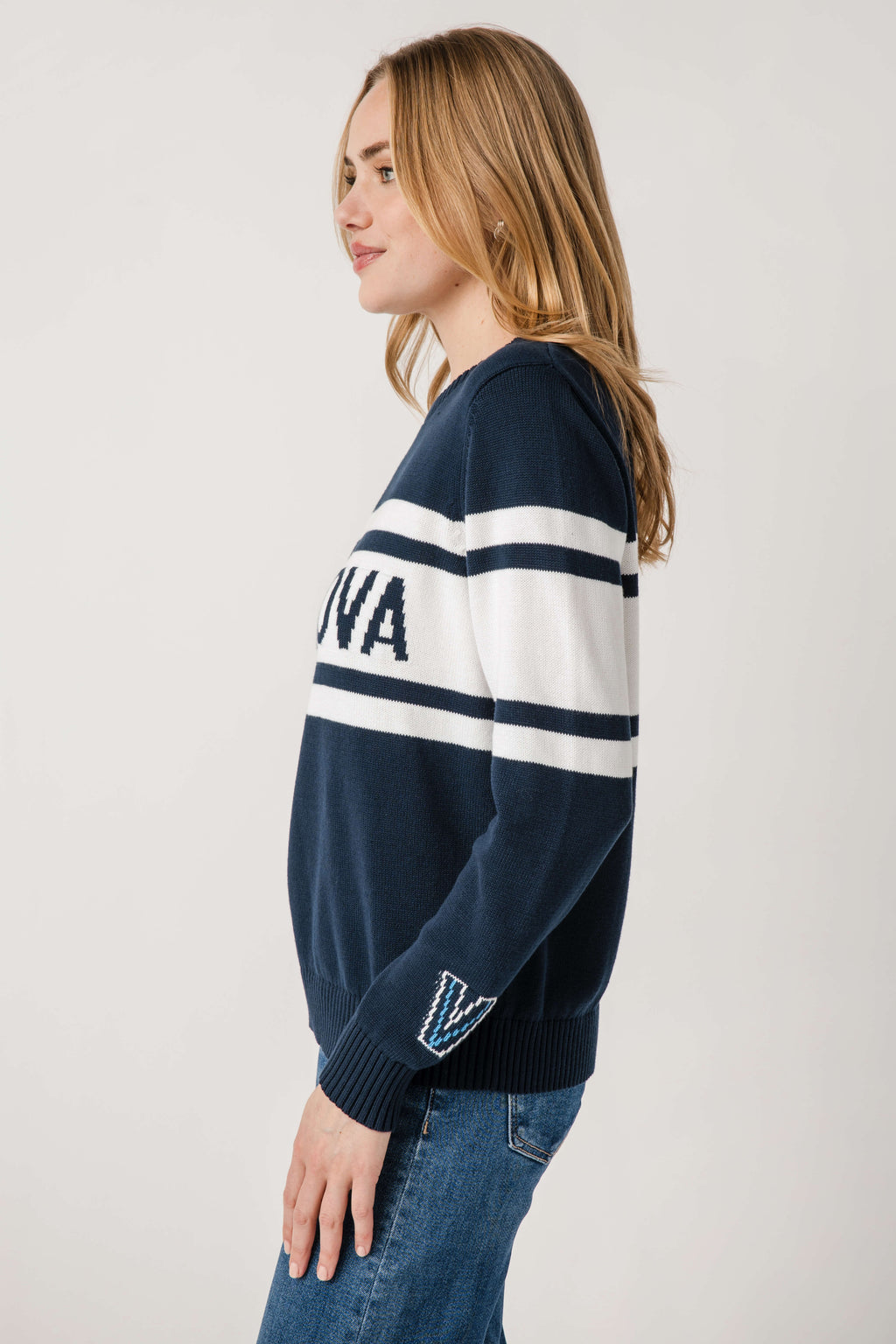 Side view of navy Villanova vintage sweater with white stripe sleeve and patch