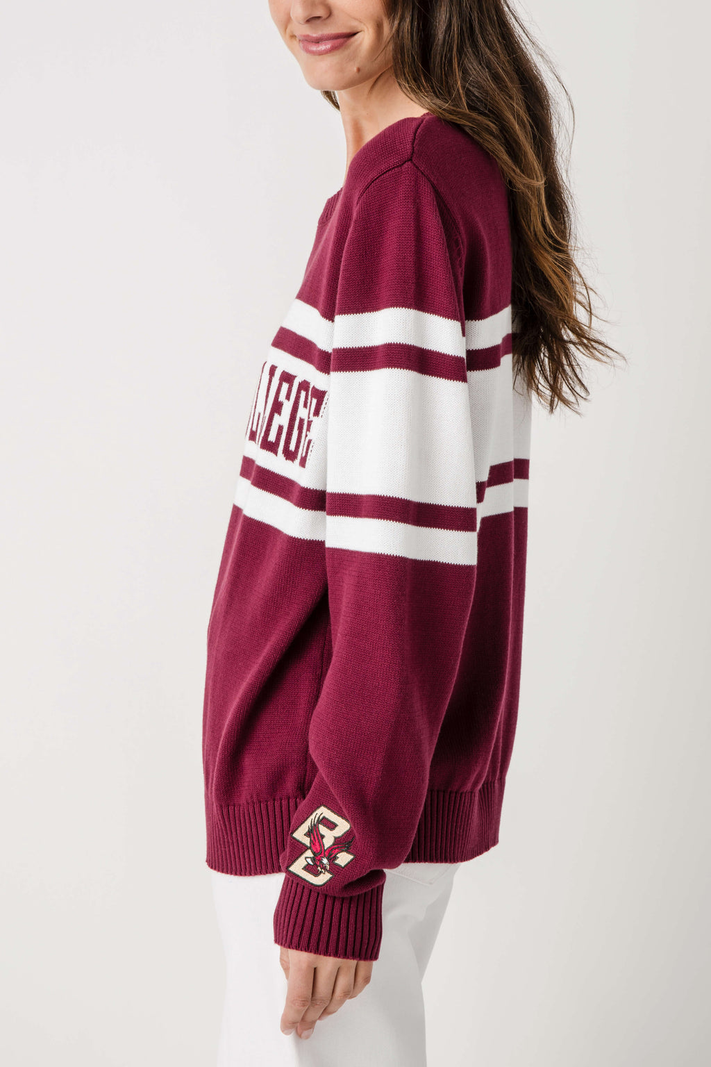 Burgundy knit sweater with wide white stripe band and school patch at cuff