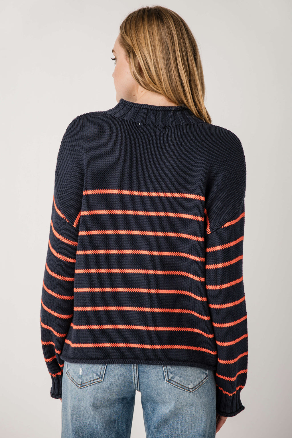 Back view of navy knit mockneck sweater with orange and black horizontal stripes.