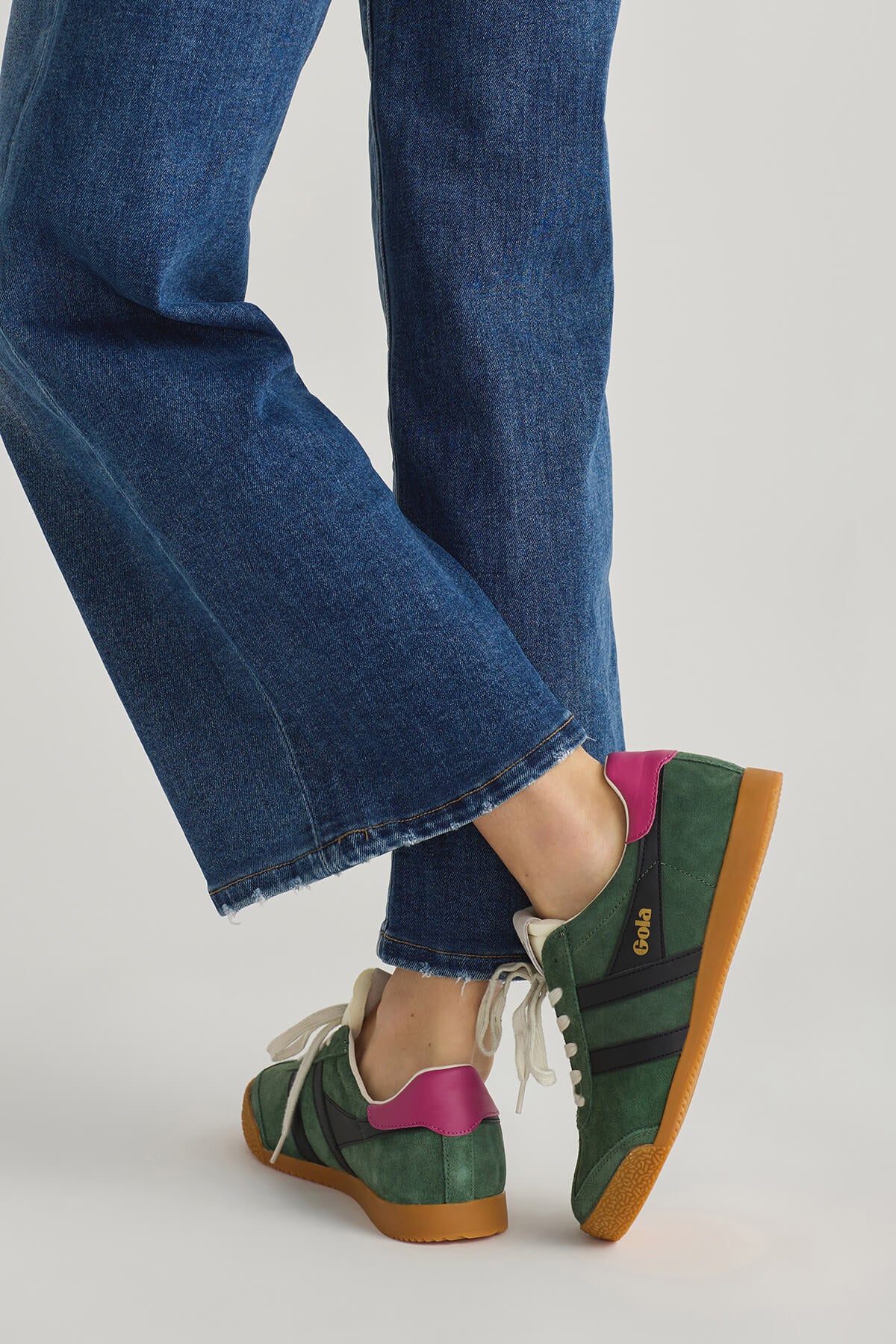 Green sneakers with white laces, purple trim, and tan outsole, angled view