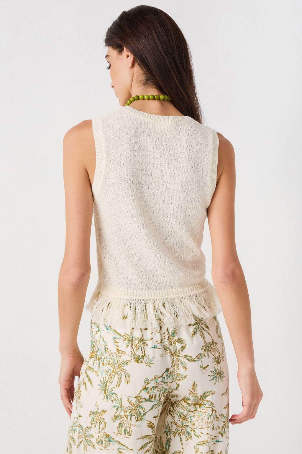 Ivory sleeveless knit top with green trim, fringe back hem