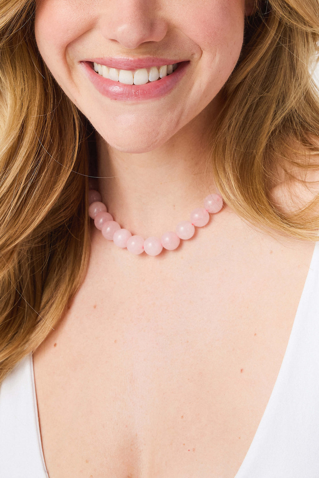 Pink crystal beaded necklace with smooth round beads, close-up at neckline