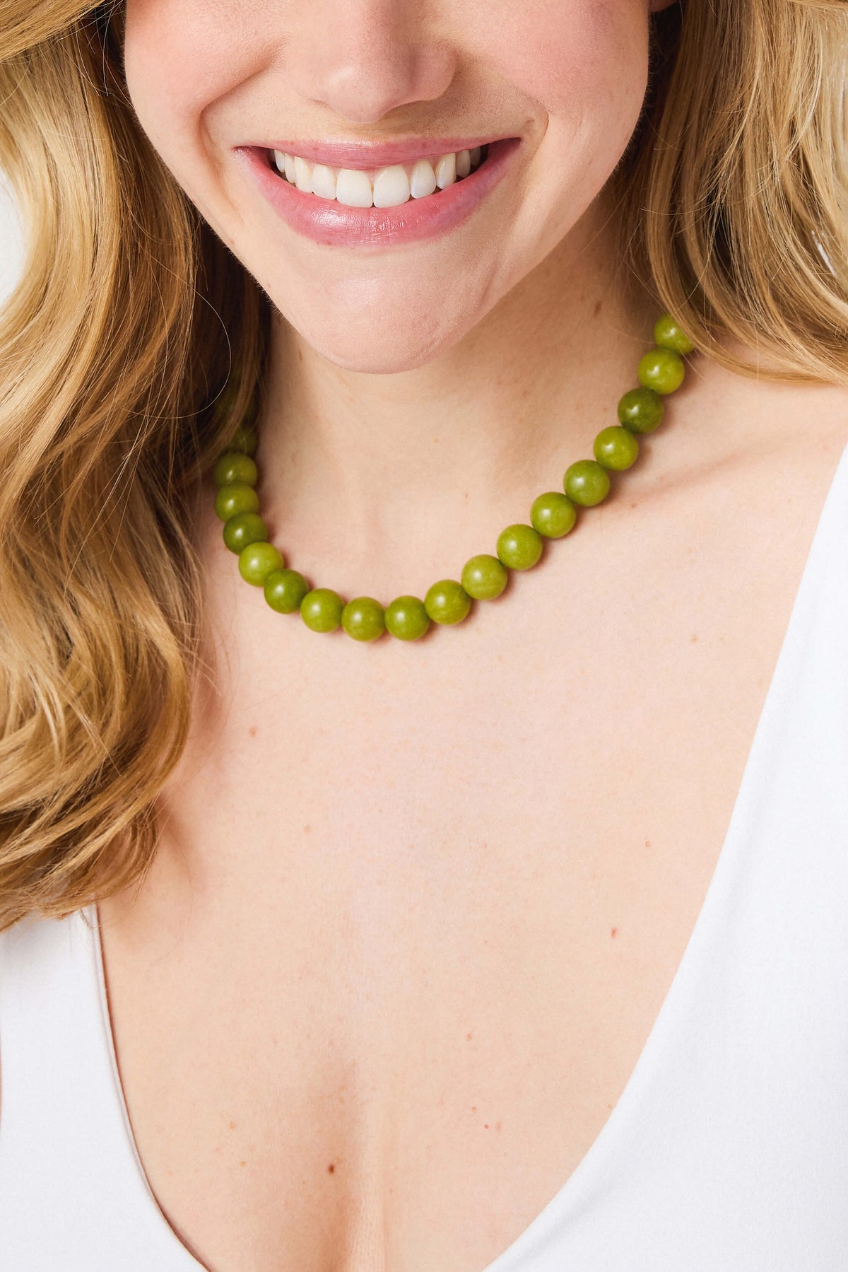 Green crystal beaded necklace with smooth round beads, close-up at neckline