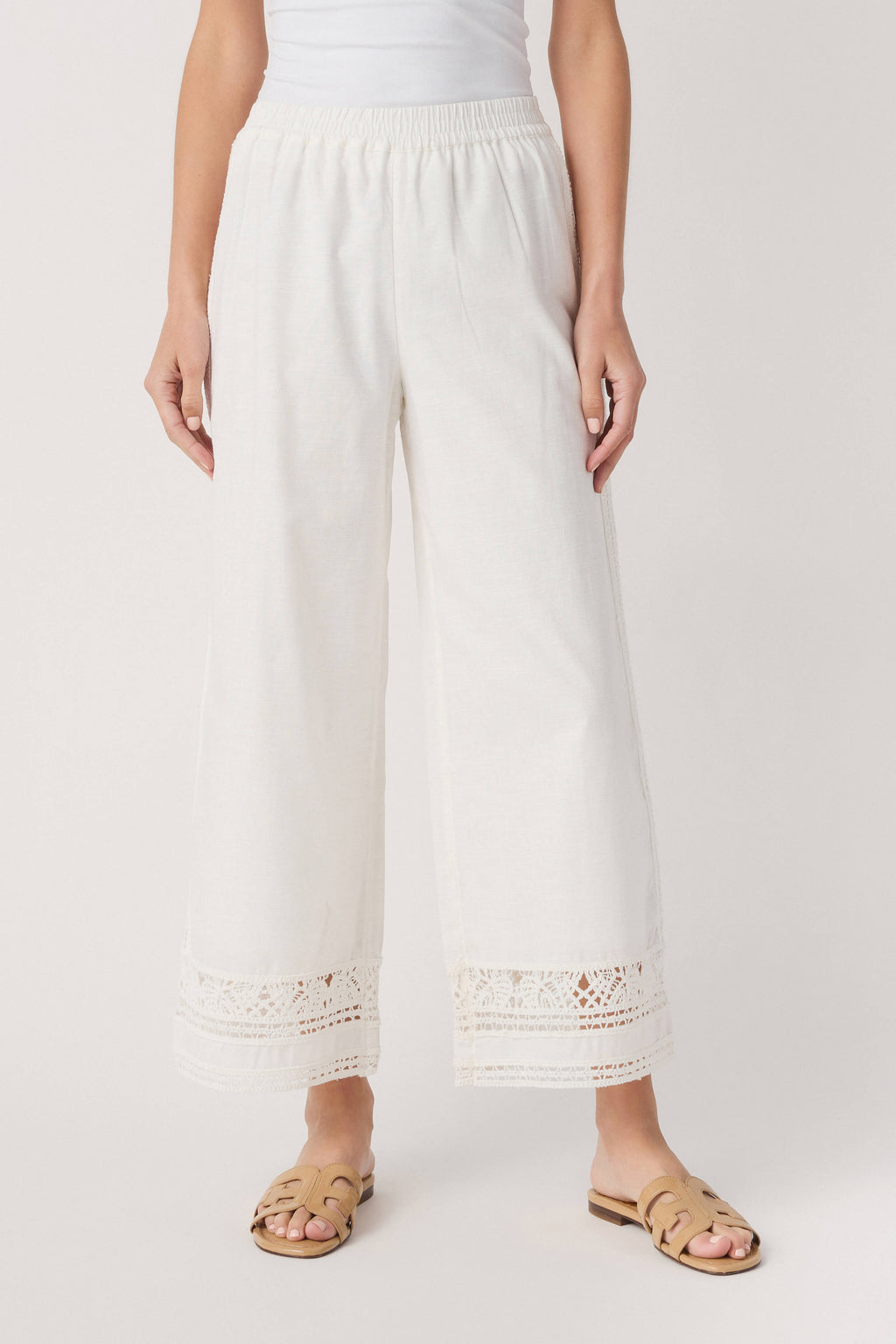 White wide-leg pants with gathered waist and embroidered eyelet trim at hem