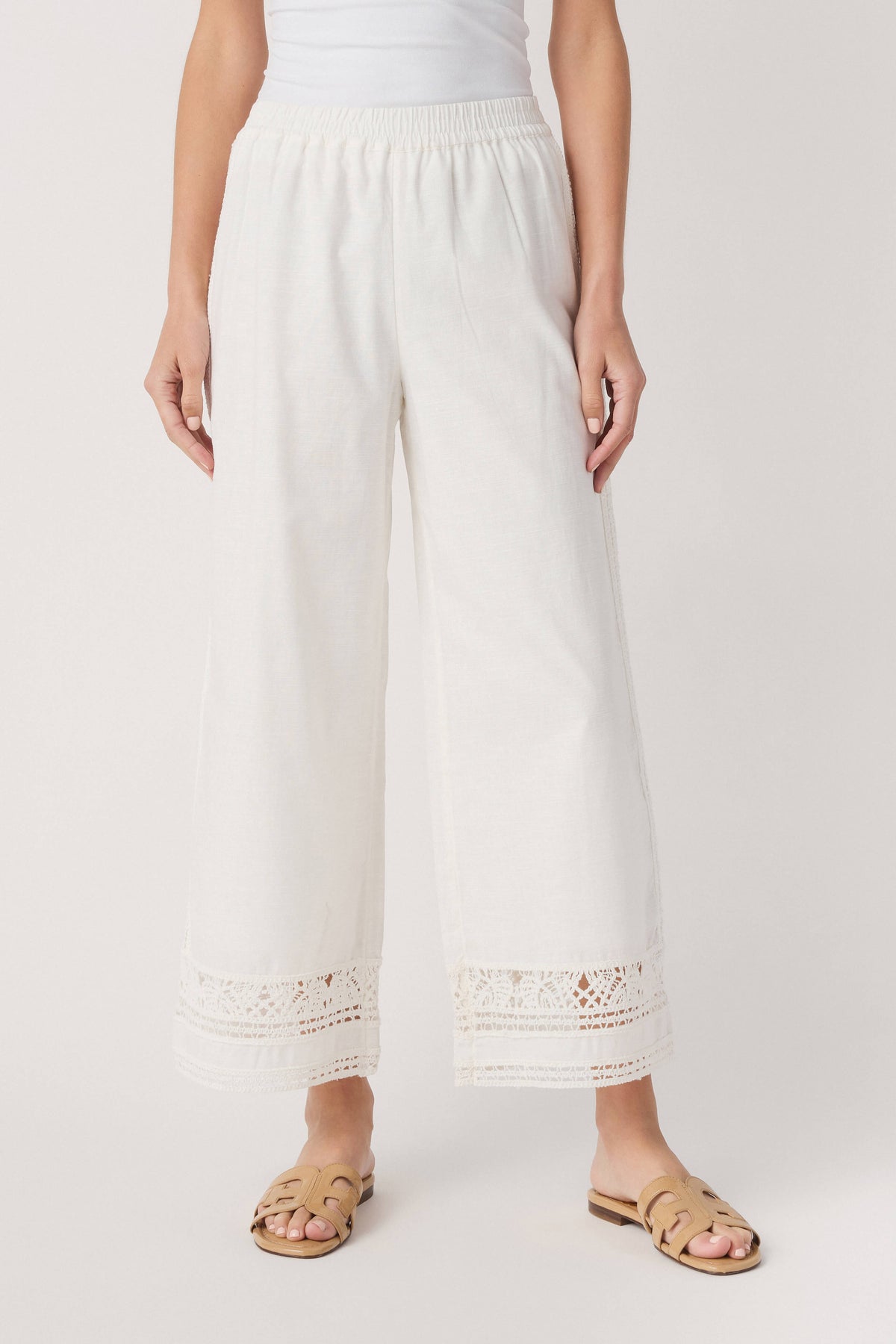 White wide-leg pants with gathered waist and embroidered eyelet trim at hem