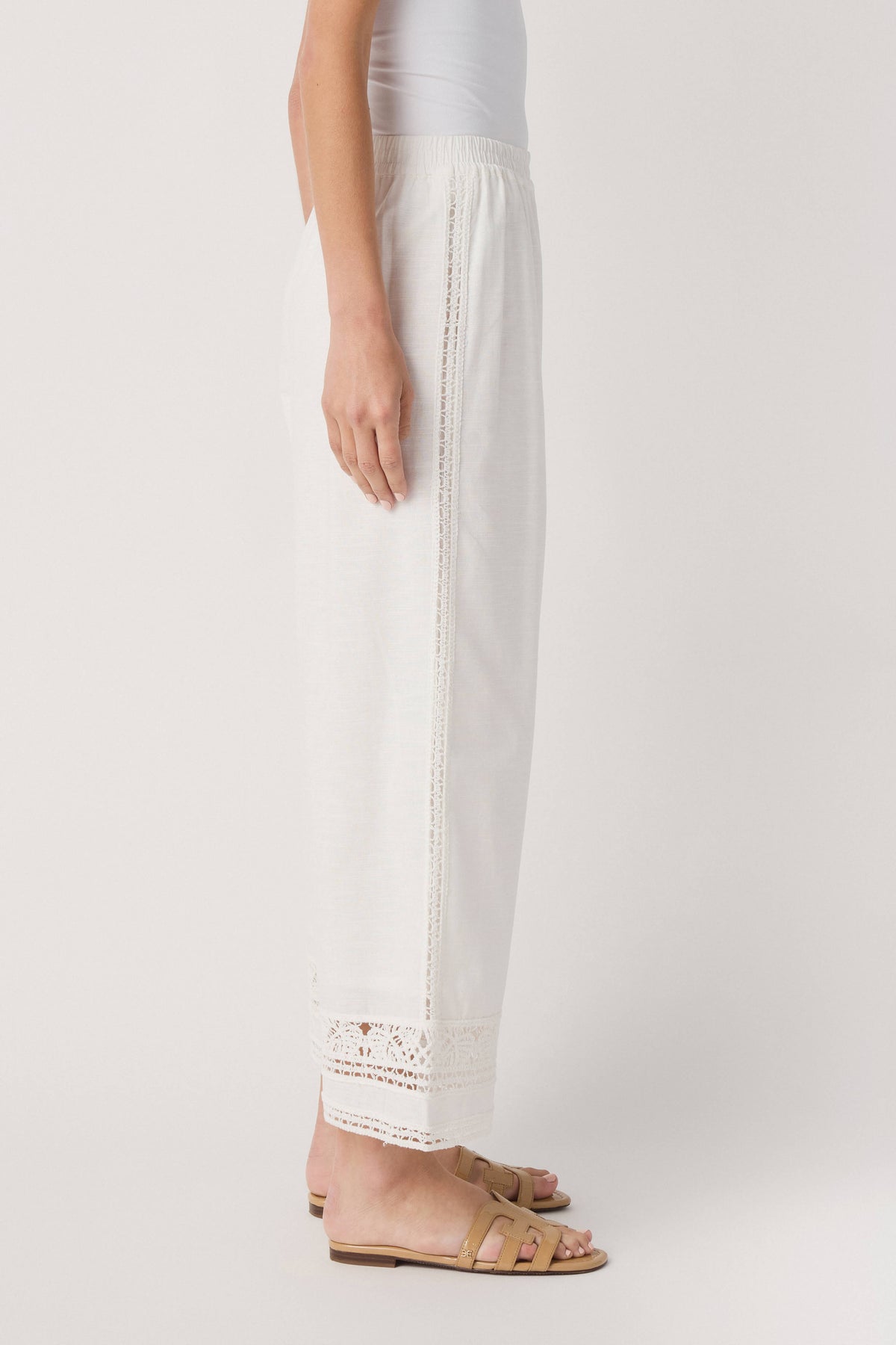 White wide-leg pants with vertical embroidered lace panel along the side