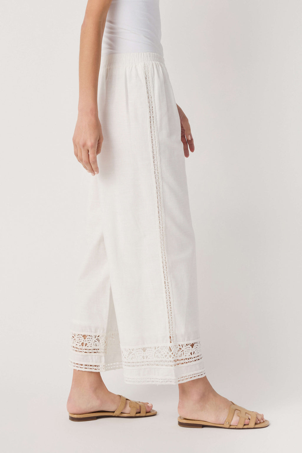 White wide-leg pants with vertical embroidered lace detail and eyelet hem