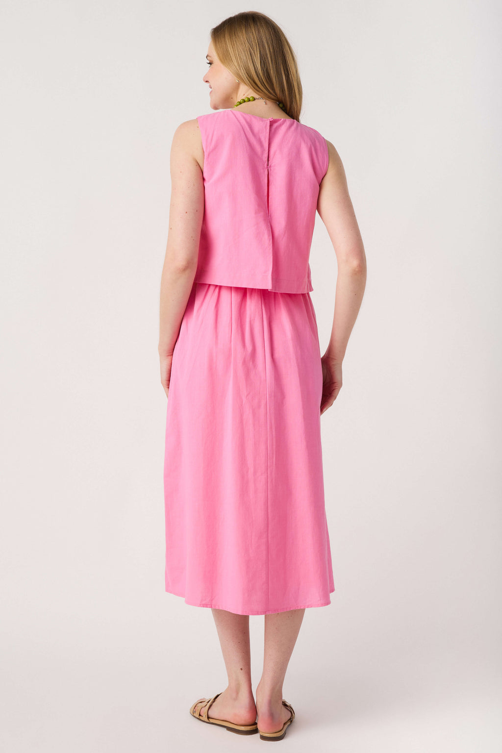 Pink sleeveless tiered midi dress, back view with round neckline and hem tiers