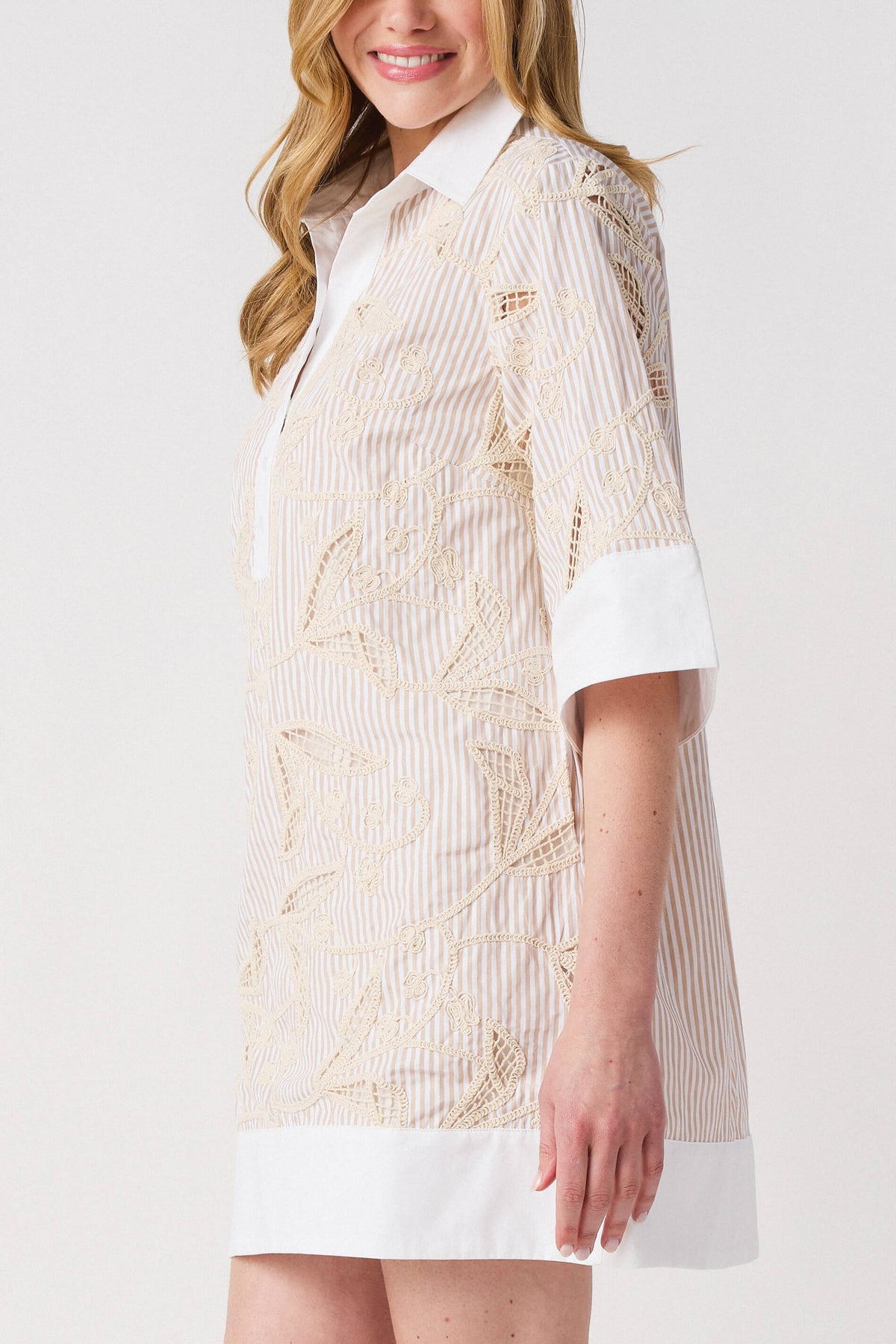Floral embroidered shirt dress detail with white button placket and collar; light taupe pattern.