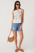 Tan rattan crossbody bag worn with perforated woven circle body and adjustable strap