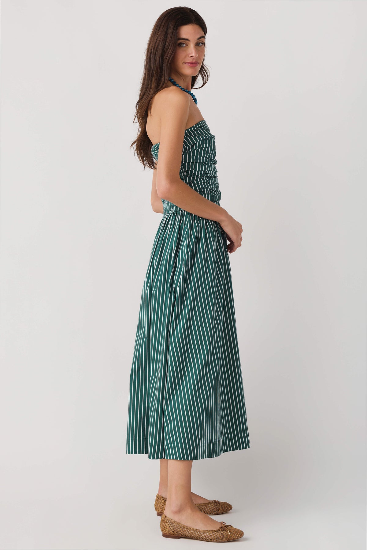 Side view of hunter green striped strapless midi dress with gathered bodice and skirt