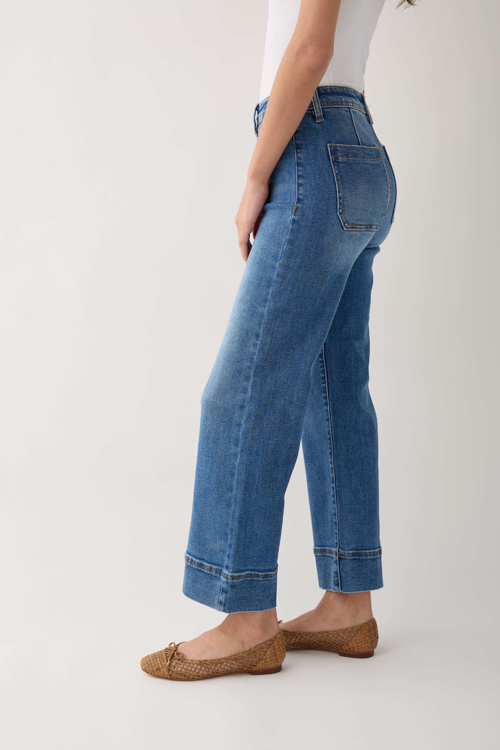 Medium-wash wide-leg ankle jeans side view with stitched pockets and cuffed hem