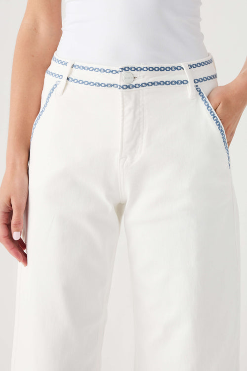 Cream cropped barrel jeans showing blue embroidered waistband trim
