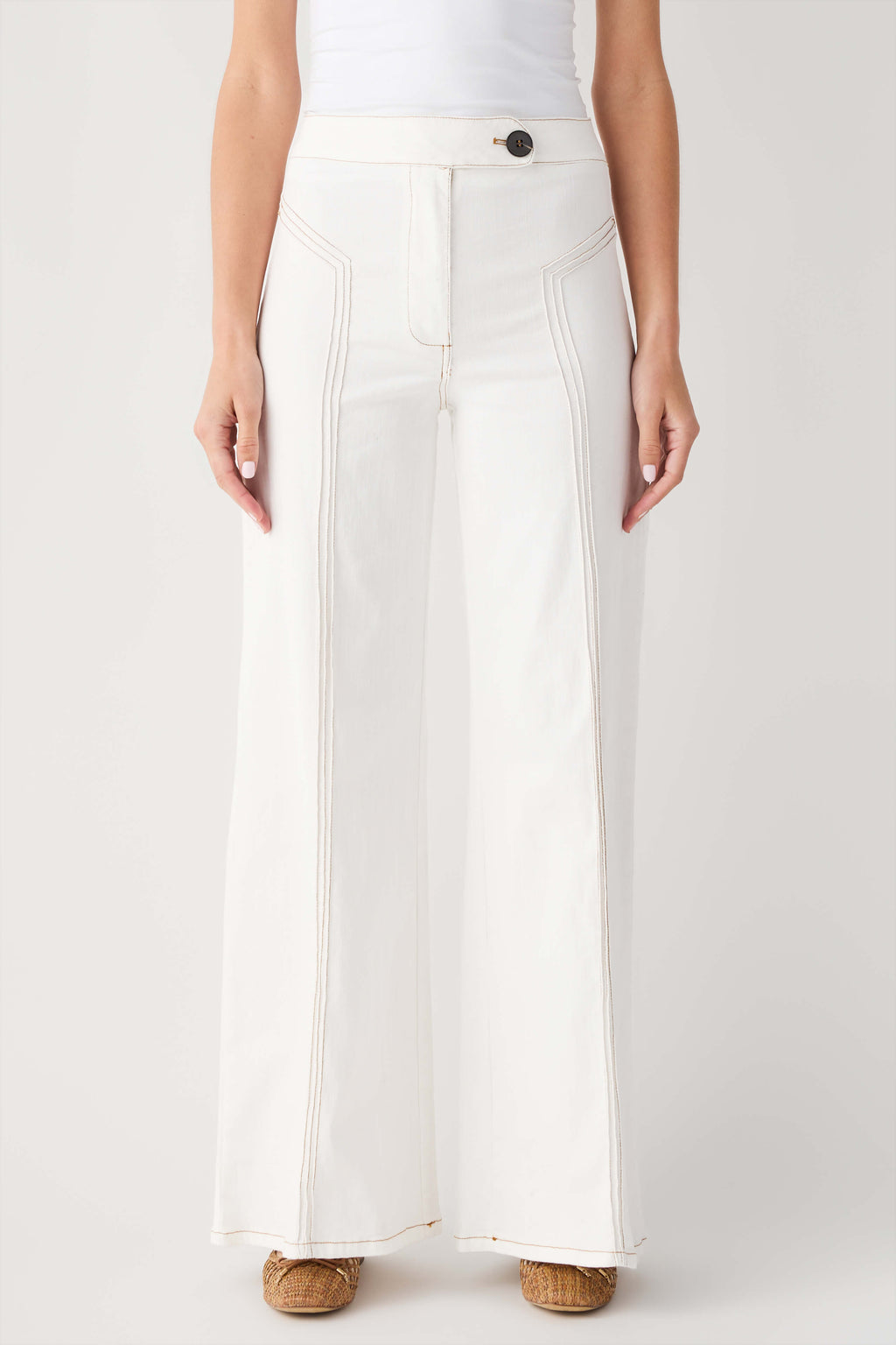Cream high-waisted flare pants with front button, belt loops, and stitched pockets.