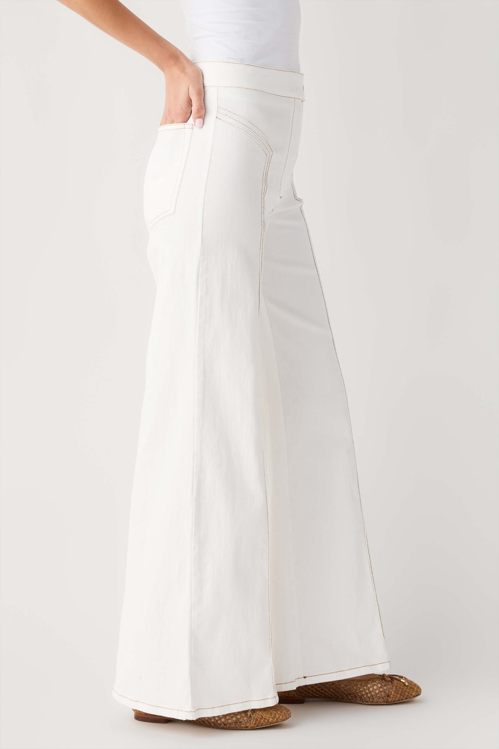 Cream high-waisted flare pants with side seams and wide bell hem.