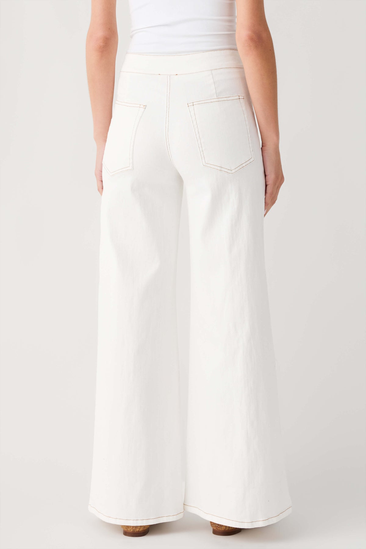 Cream high-waisted flare pants, back view with stitched pockets and straight waistband.