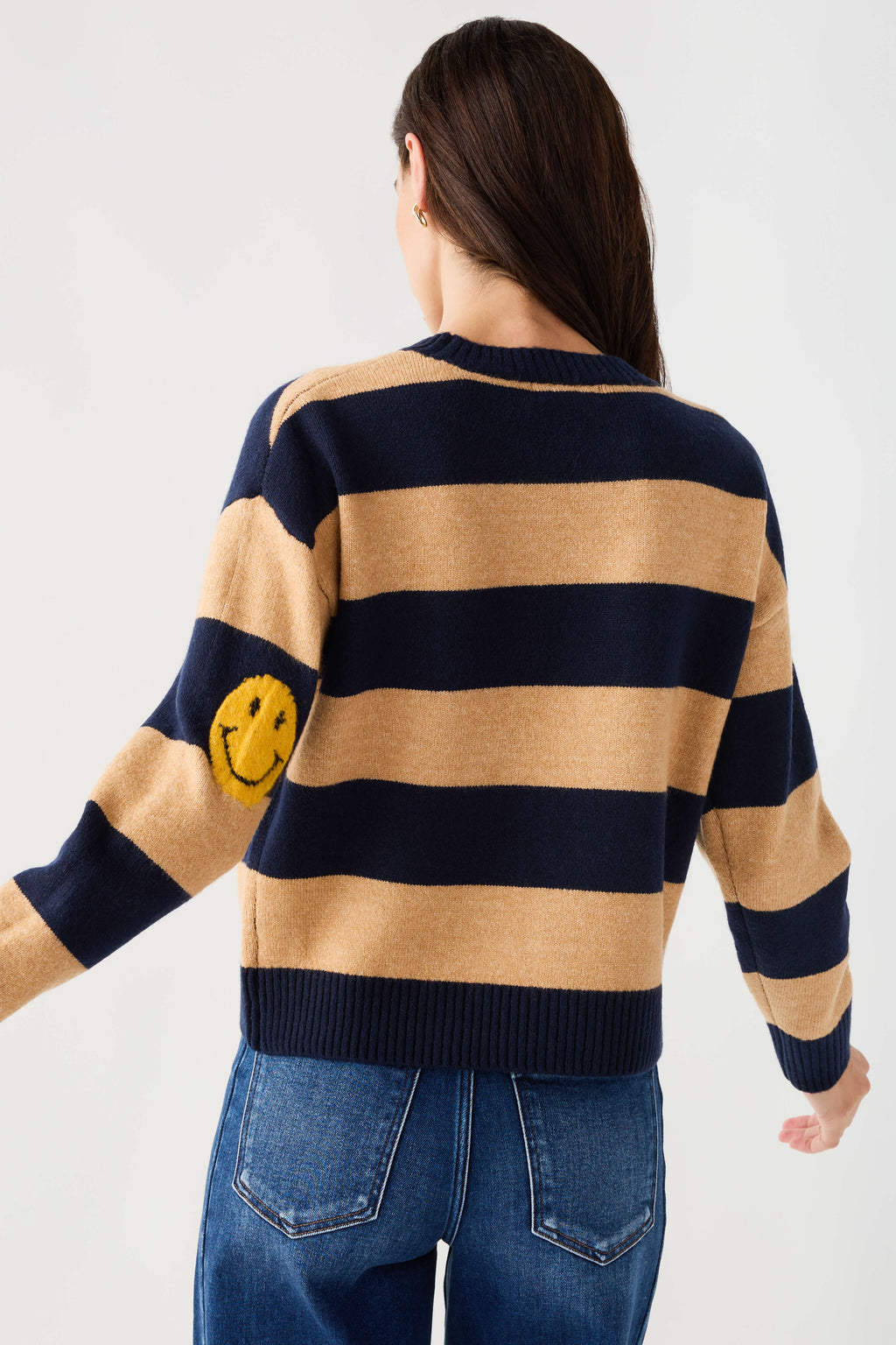 Back view of navy and camel striped sweater with smiley face patch near shoulder