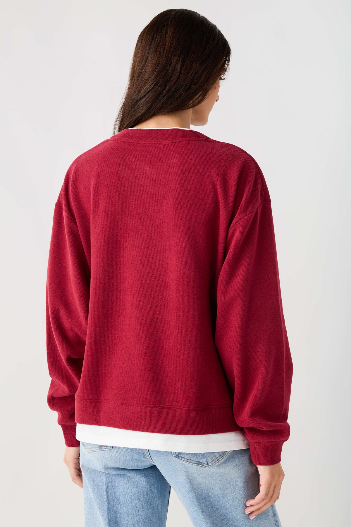 Back view of cranberry red crewneck pullover with ribbed cuffs and white hem band.