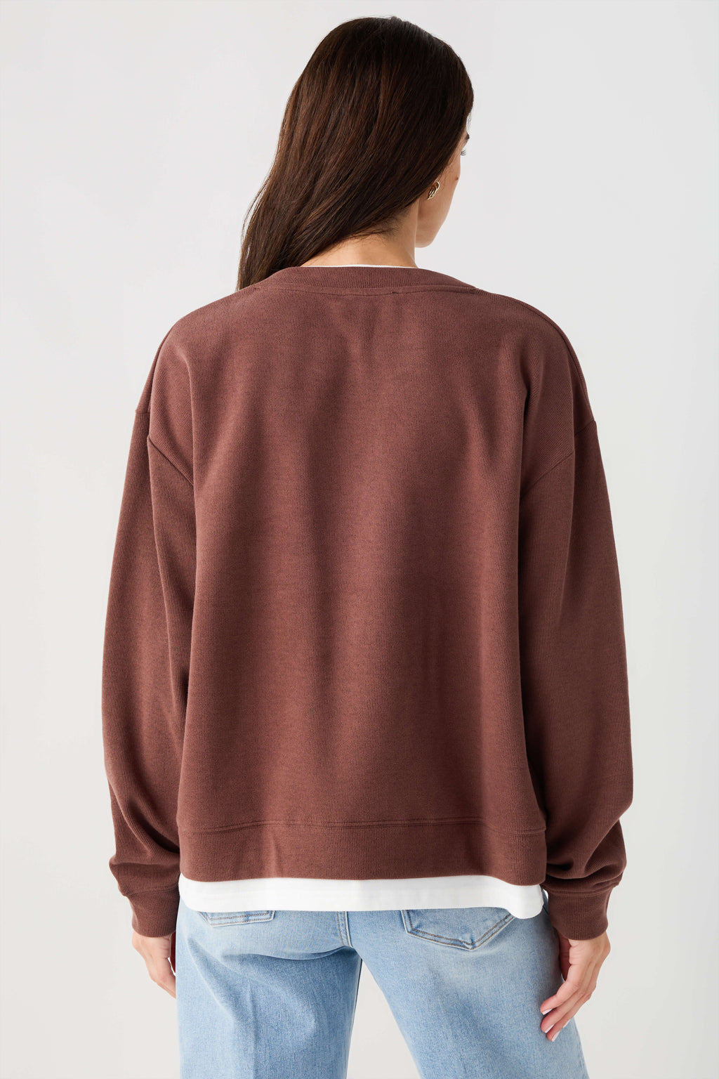 Back view of chocolate brown crewneck pullover with ribbed cuffs and white hem band.