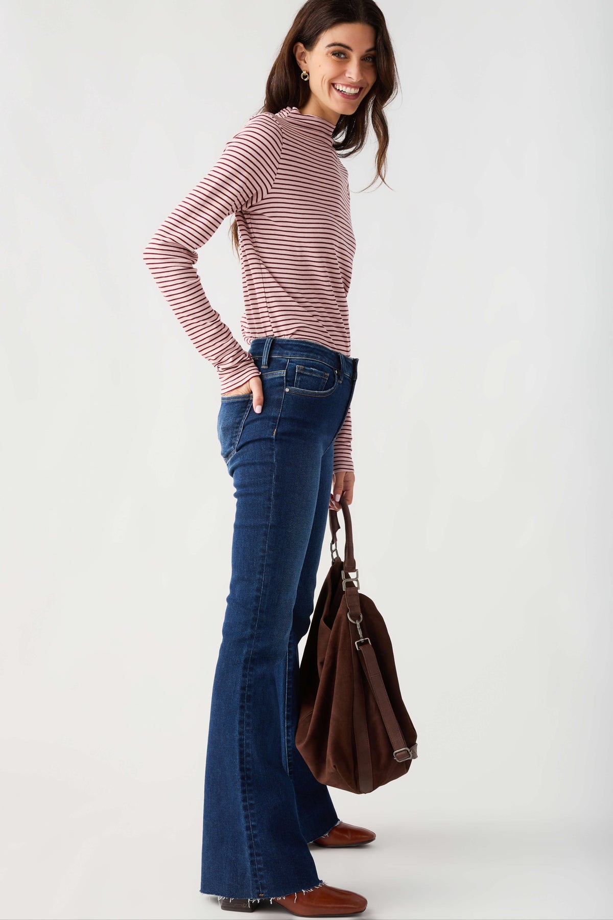 Dark brown suede slouch tote held at side, with short handles and crossbody strap