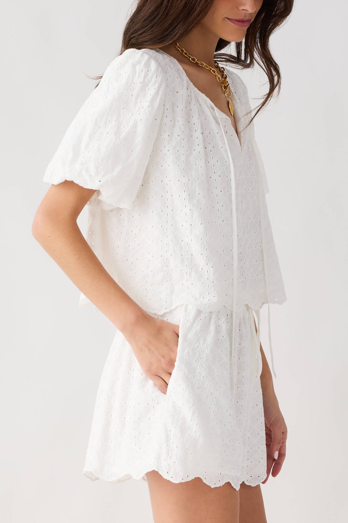 Off white eyelet lace top with V-neck and puff sleeves, layered tiered skirt-like hem
