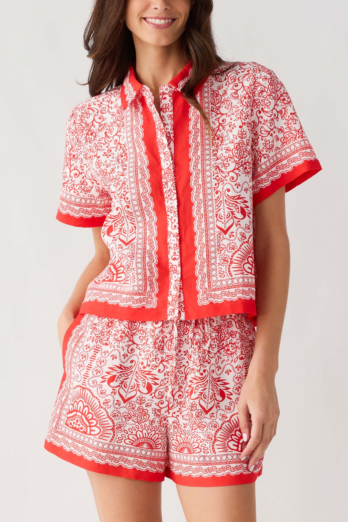 Red and white border-print short set top close-up with button-front placket and vertical panel