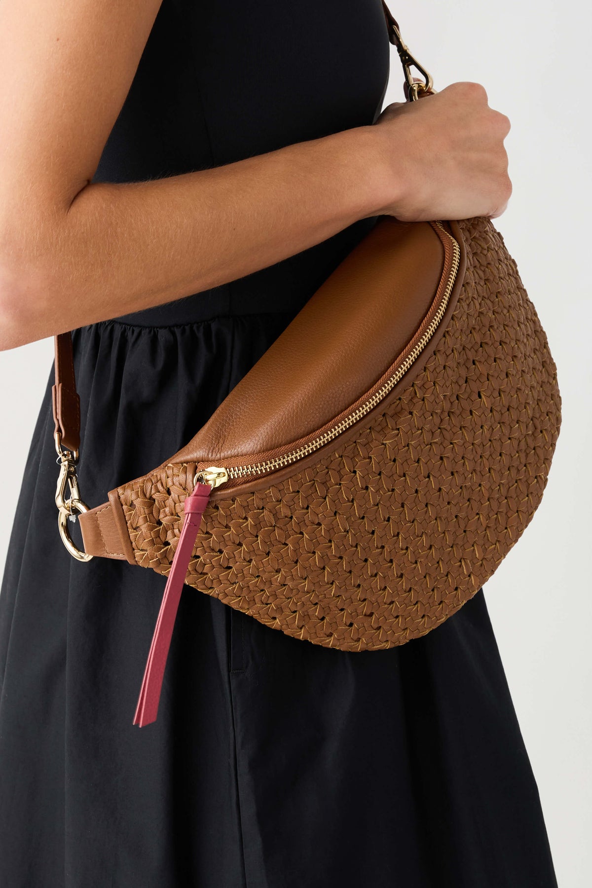 Camel woven half-moon sling bag with zip, leather trim, and pink tassel keychain