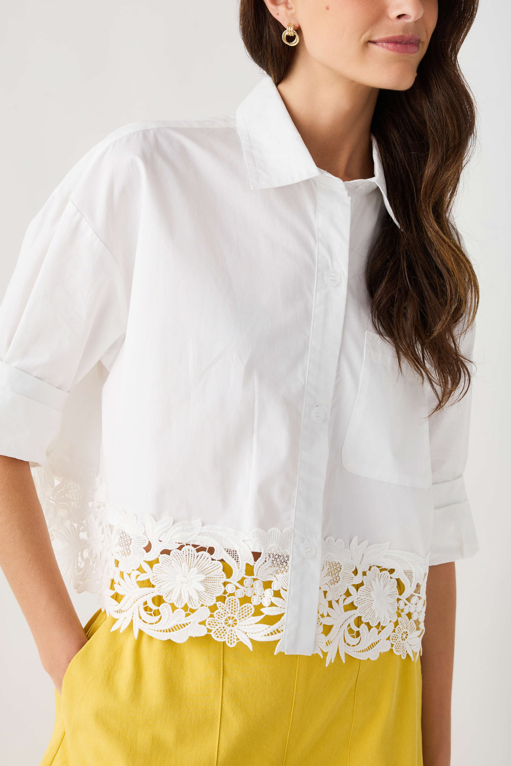 White poplin top with chest pocket, lace hem trim, and button placket