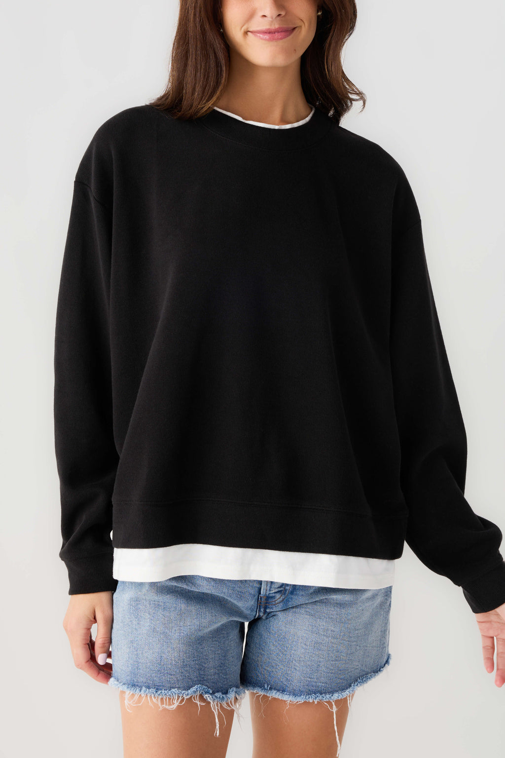 Crewneck pullover sweatshirt in black with ribbed cuffs and white hem band.