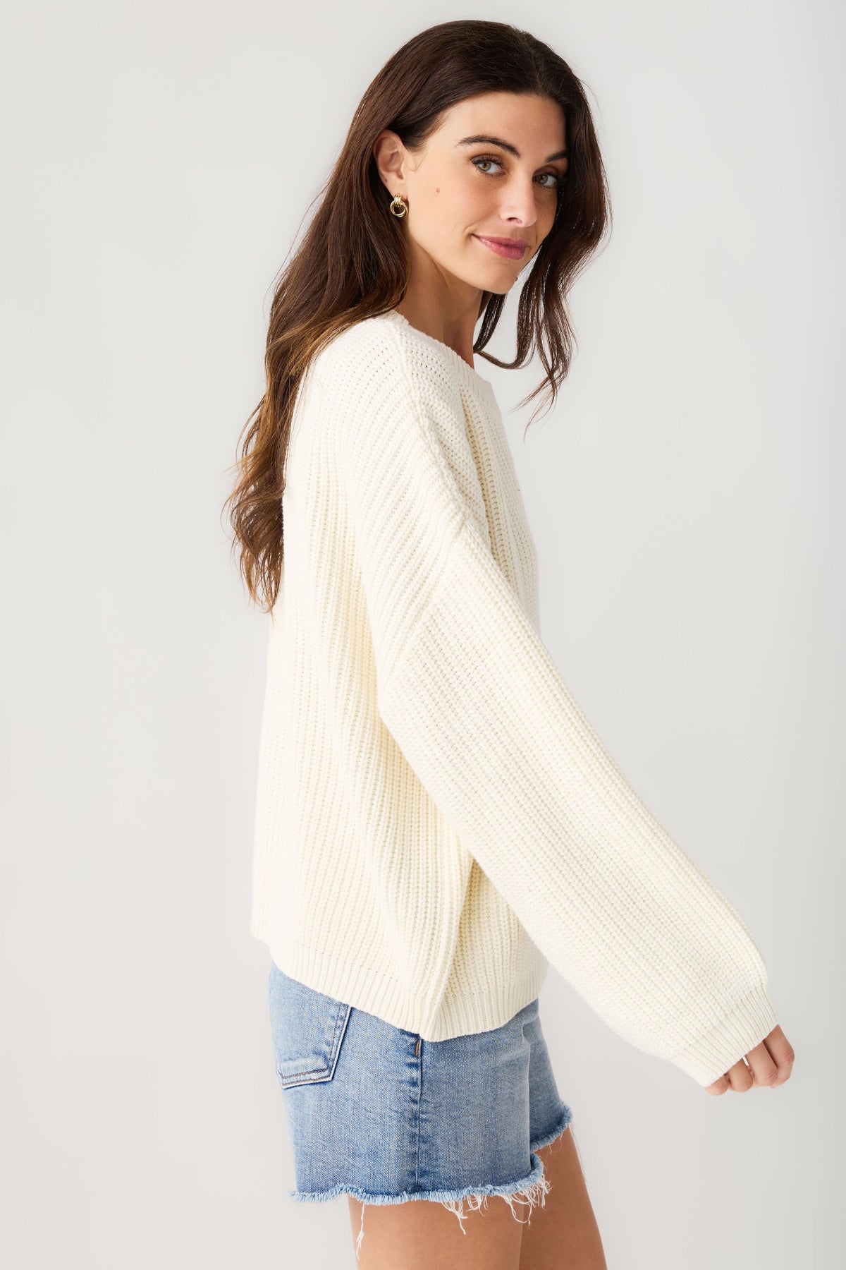 Cream knit pullover top, side view with long sleeves and ribbed hem