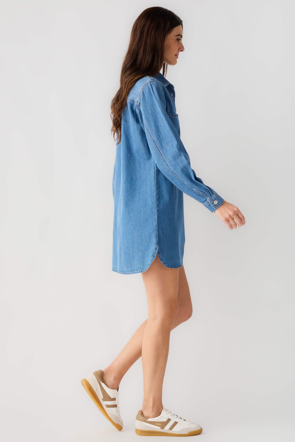 Blue denim shirt dress with collar, button front and long sleeves, side view.