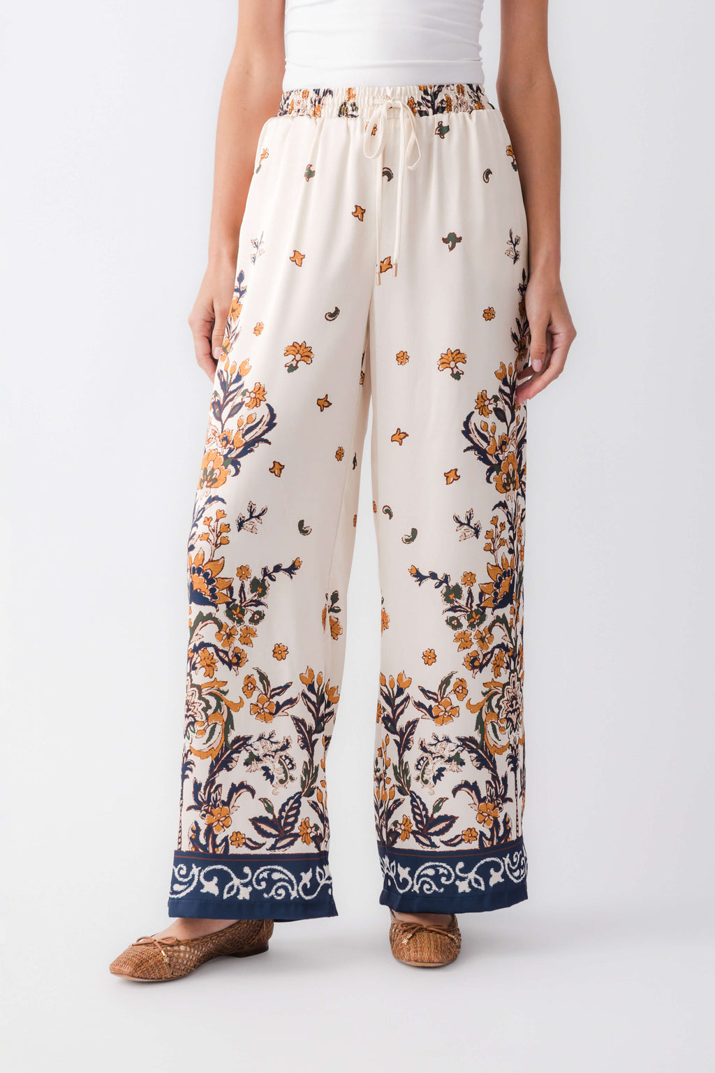 Ivory satin wide-leg pants with large floral motifs and navy cuff border