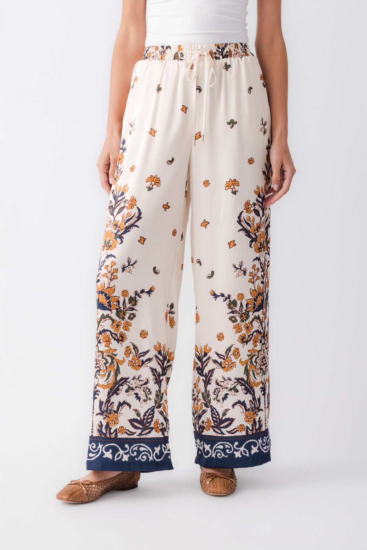 Ivory satin wide-leg pants with large floral motifs and navy cuff border