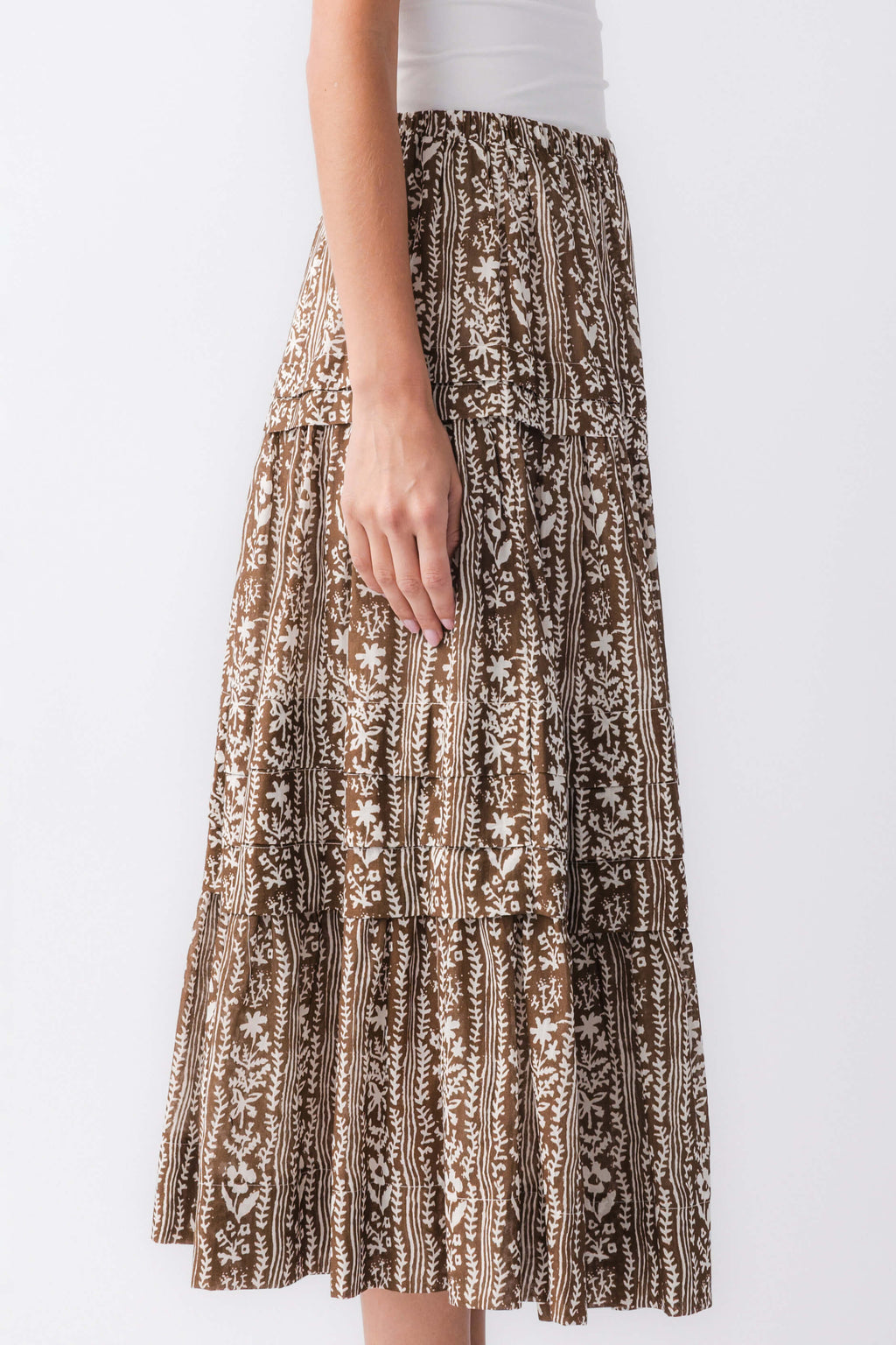 Close-up of mocha printed tiered maxi skirt hem with gathered ruffle layers, brown/black