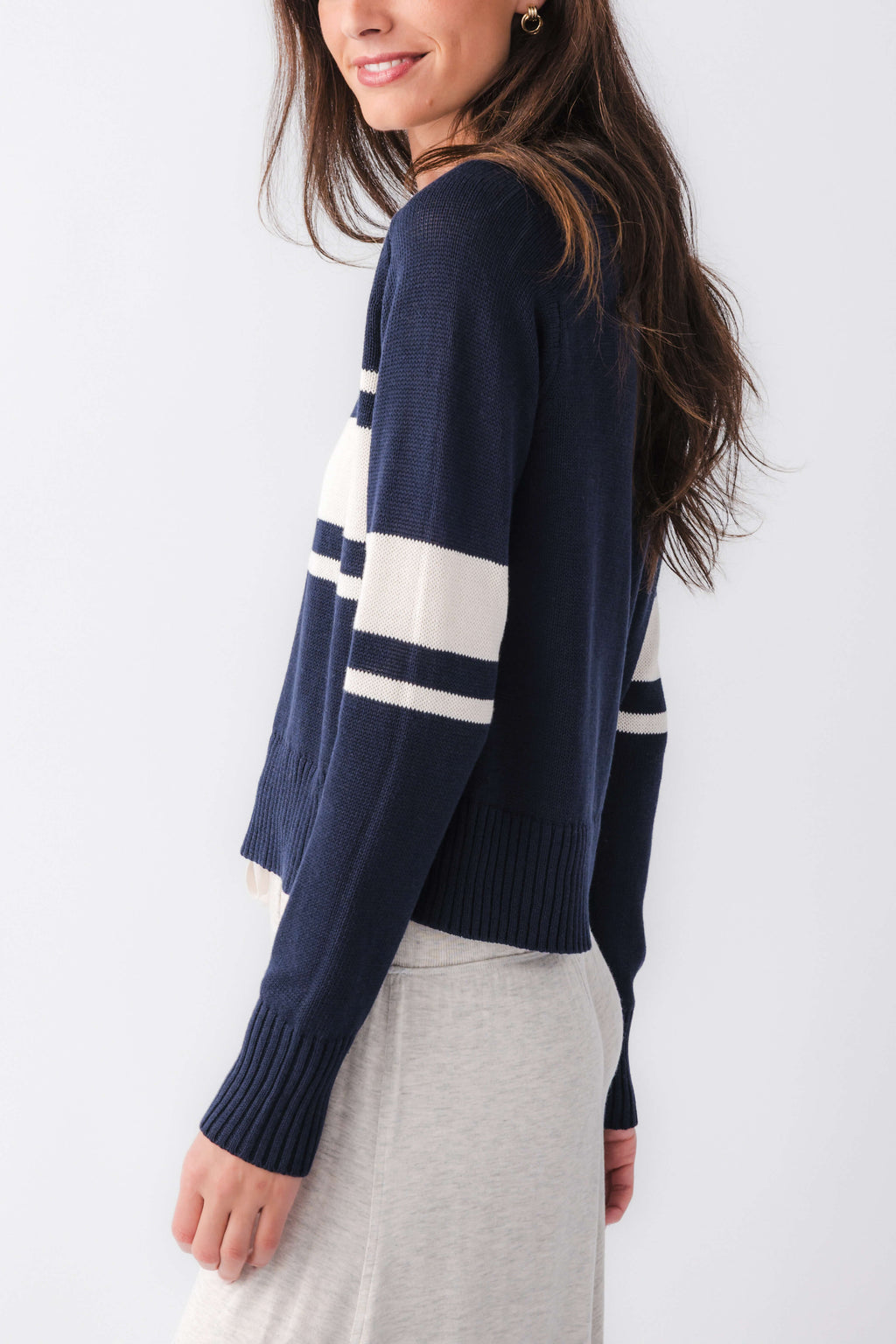 Navy knit sweater with cream stripe panel and long sleeves, side view