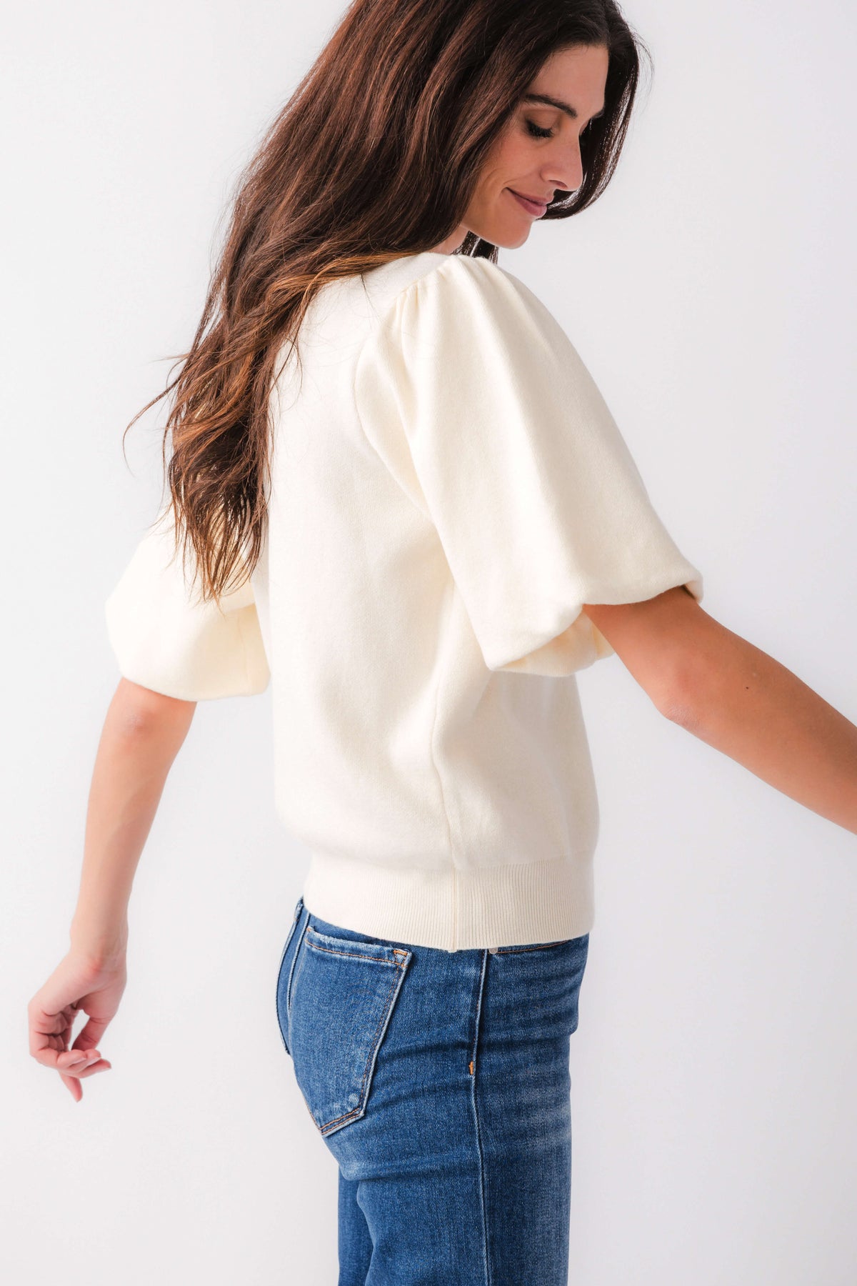 Cream knit bubble-sleeve top shown from the side, crew neckline