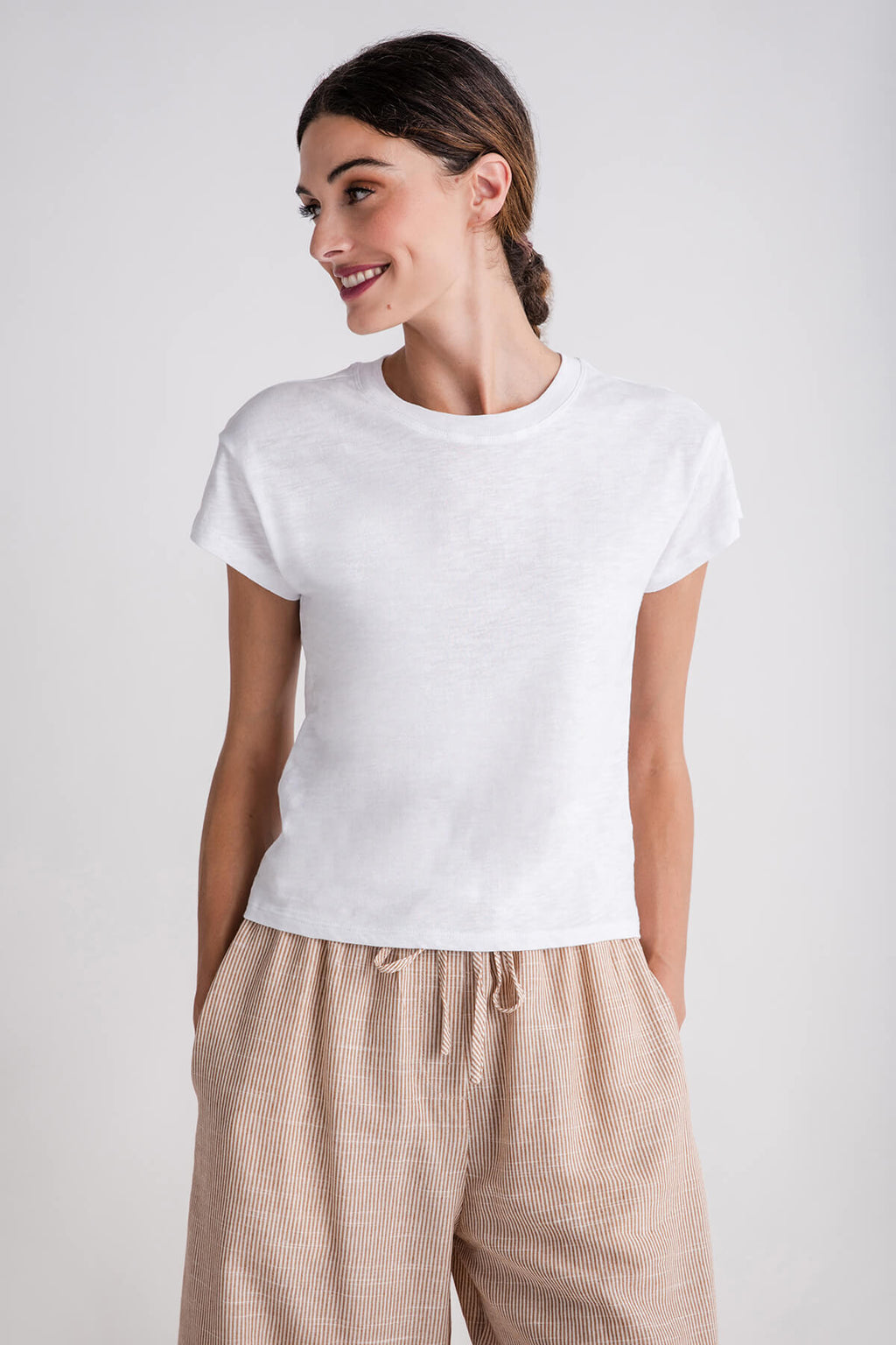 White modern slub tee with short sleeves and crew neck, layered over beige pants
