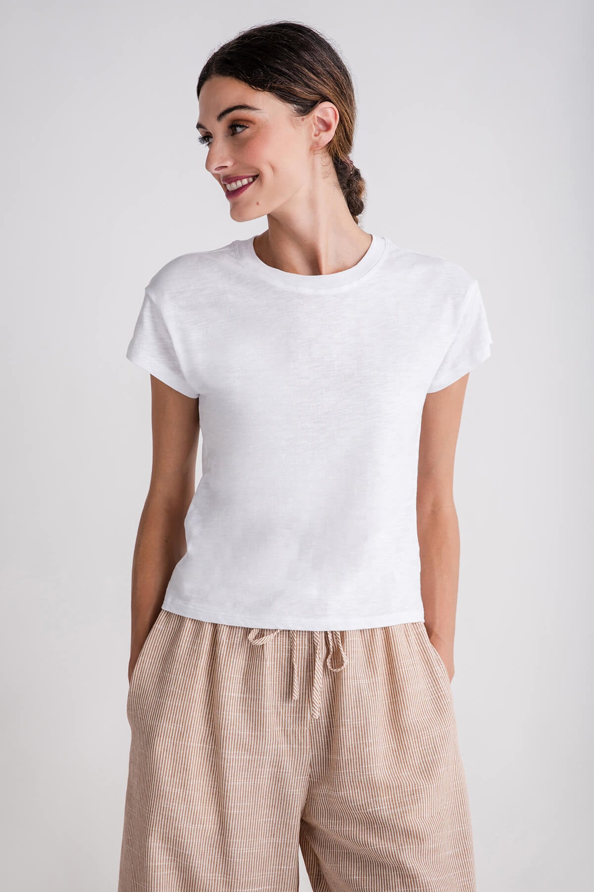 White modern slub tee with short sleeves and crew neck, layered over beige pants