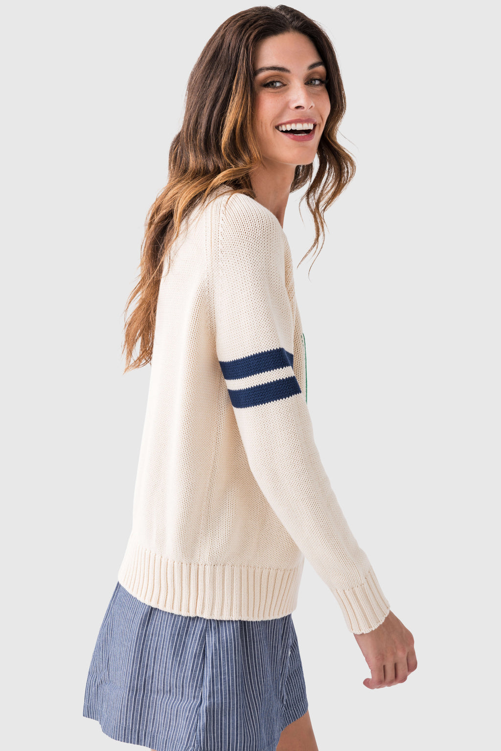 Cream knit sweater with navy-striped sleeve and ribbed hem