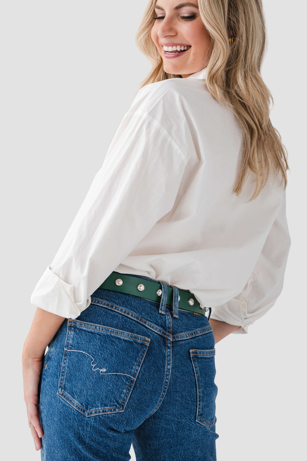 Emerald studded belt with gold grommets on dark blue jeans