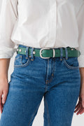 Emerald stud belt with square buckle and gold eyelets, worn on jeans